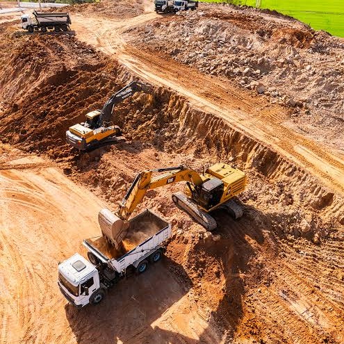 Escavadeiras realizando terraplenagem e carregamento de caminhão em obra